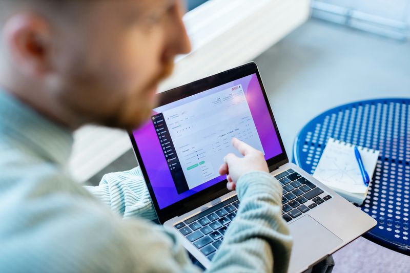 A man pointing at a laptop with a window of figures showing.