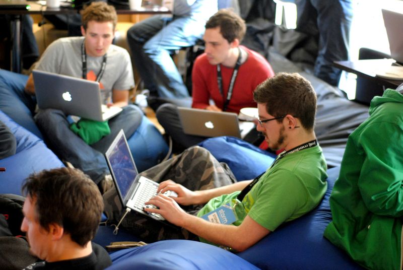 A group of office workers using laptops on beanbag chairs.