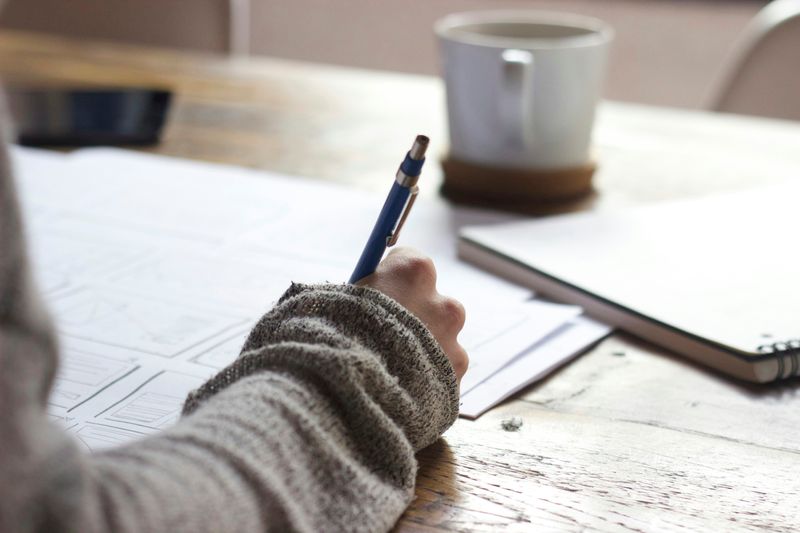 A person writing on a sheet of paper.