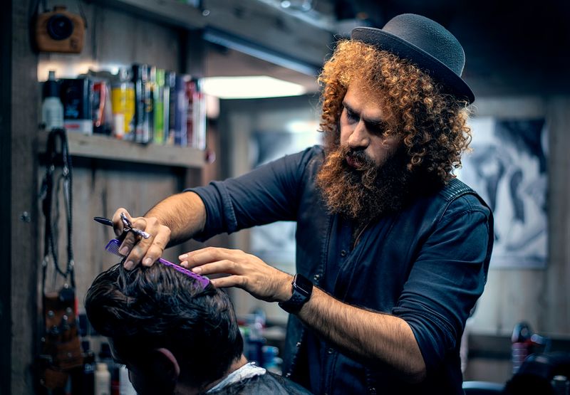A male hairstylist cutting hair.