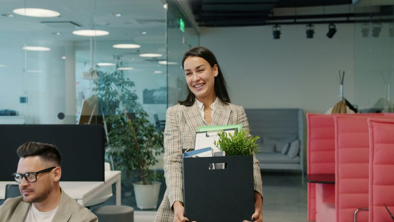 A smiling woman moving into a new office.