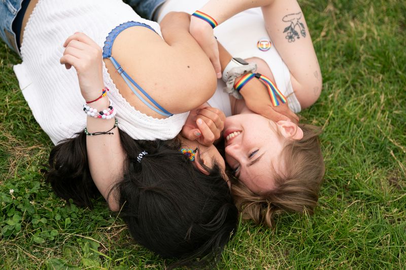 A couple laying on the grass smiling at each other.