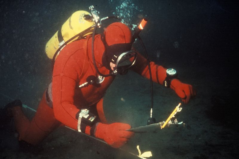 An underwater surveyor using measuring tools while scuba diving