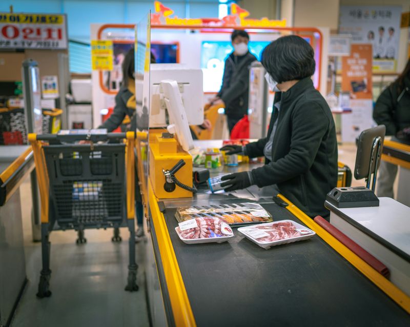 The checkout counter at a grocery store. An employee rings items through a scanner.