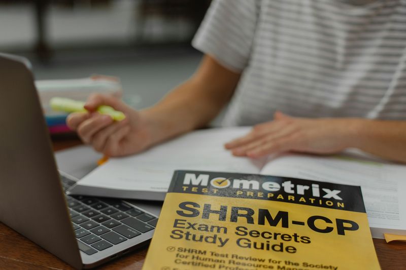 A person studying for the SHRM exam with a study guide.