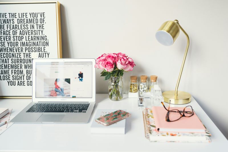 A well-organized work space with flowers on a desk and inspirational statements in a picture frame.