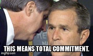 An advisor leans into George W. Bush's ear. He tells him, 