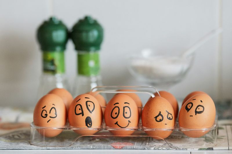 Eggs in a plastic egg holder. Each egg has a face drawn on it with  marker to represent different emotions.
