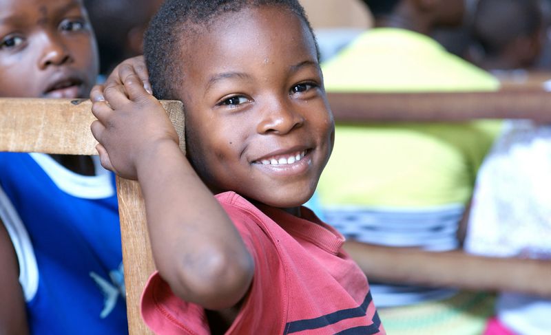 Two boys, one smiling in the foreground, the other blurred in the background.