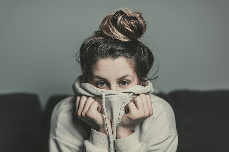 A person slouching and hiding part of their face with their hoodie.