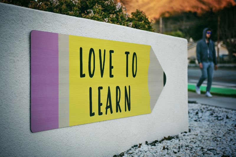 A sign on a college campus shaped like a pencil displays the phrase 'Love to learn'.