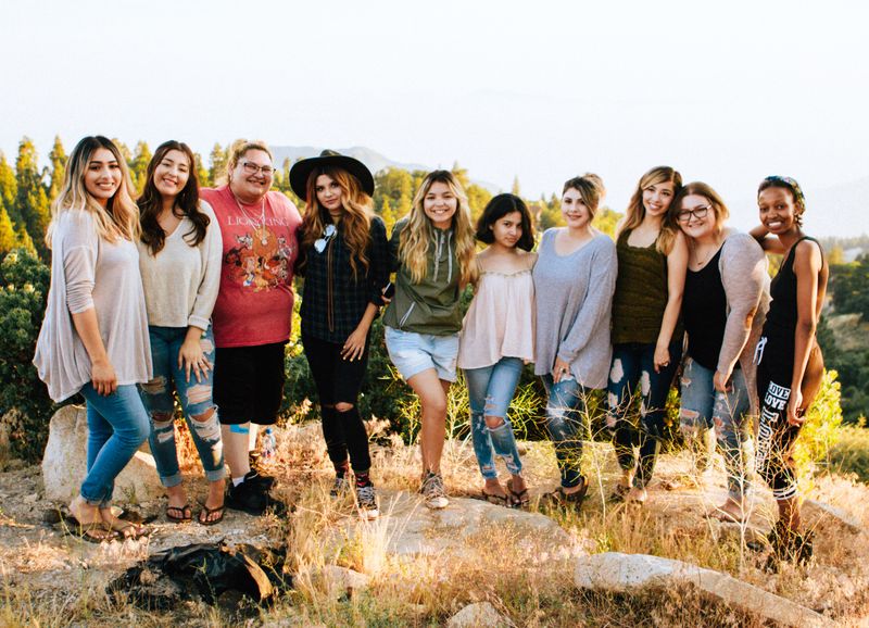 Women from different ethnicities posing for a picture on a hiking path.