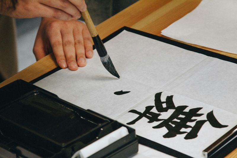 A person writing Japanese Kanji in calligraphy.