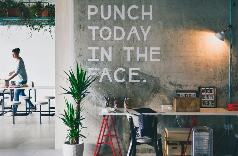 A modern office space.  On a gray wall, the words 'Punch today in the face' appear.