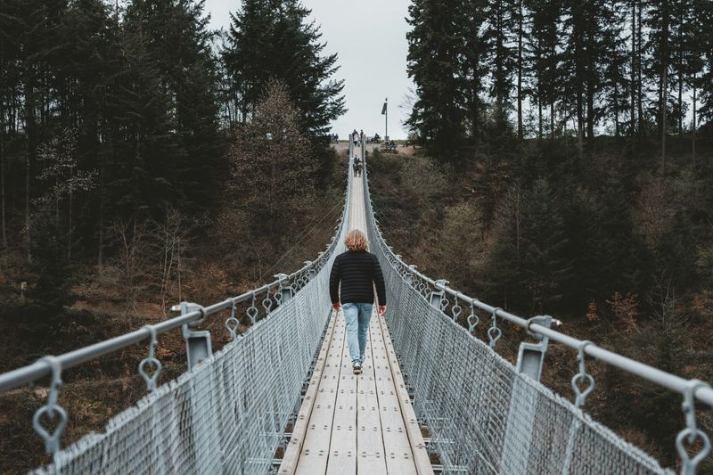 A person walking across a long bridge toward their destination.