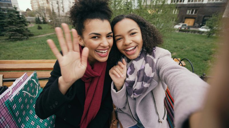 Two smiling people on a bench, taking a selfie with each other.