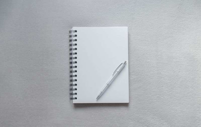 A blank notebook and a pen on a table.