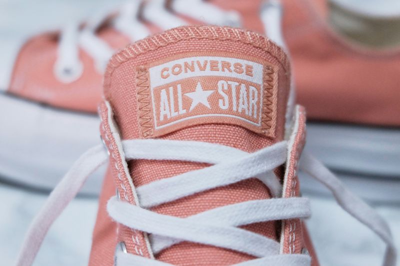 The unlaced tongue of a pink Converse All Star shoe.