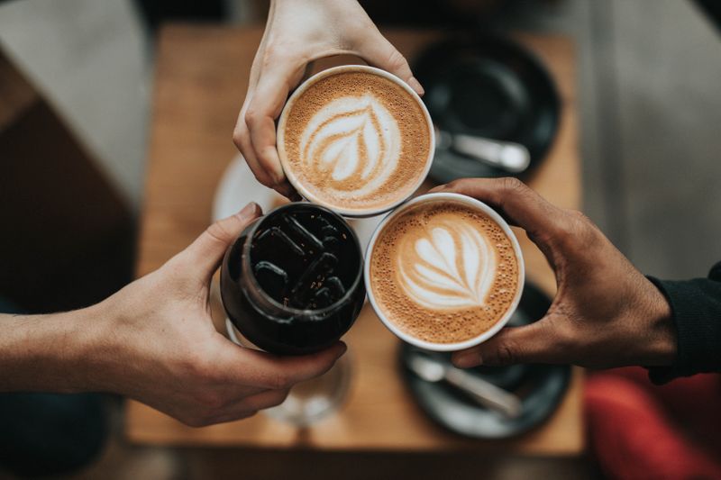 Three hands holding coffee mugs.