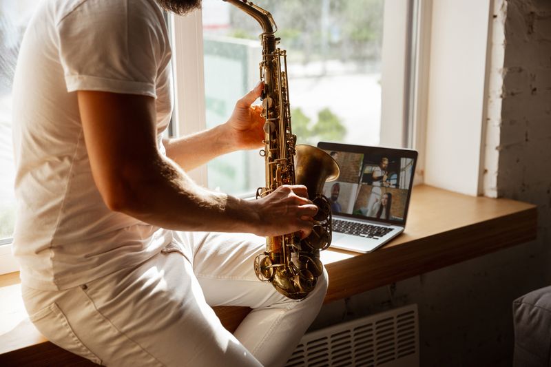 Man plays saxophone with people online.