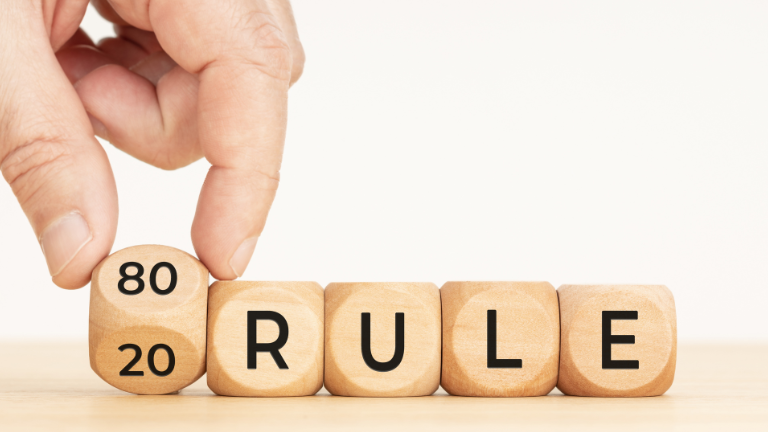 An image of a hand holding a cube with 80-20 on it. The rest of the cubes make the word rule.