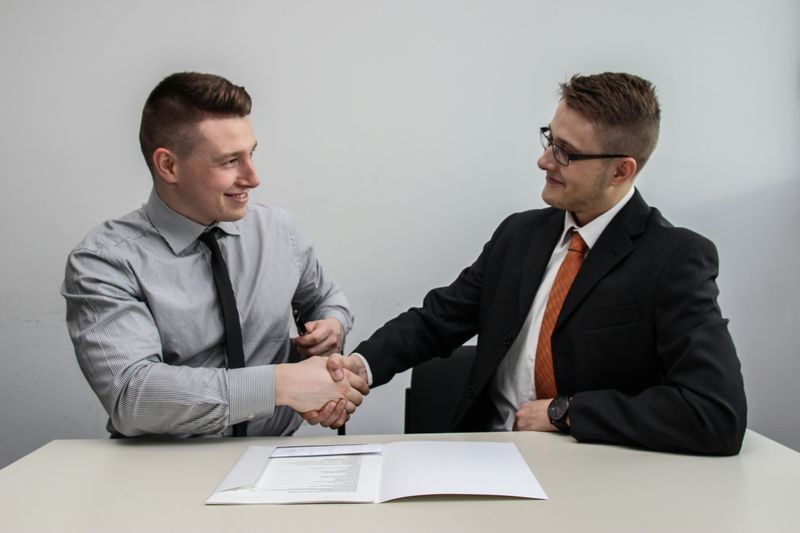 Two men are shaking hands over a resume.