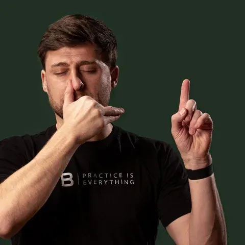 Man doing breath work exercise with one hand while holding up the other hand for a count of four.