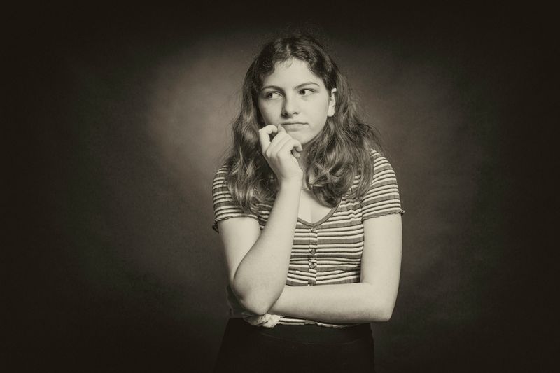 Serious person in a thinking pose, looking in the distance with one hand touching their chin 