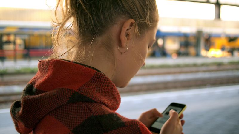 A woman looks down at her phone, scrolling through content.