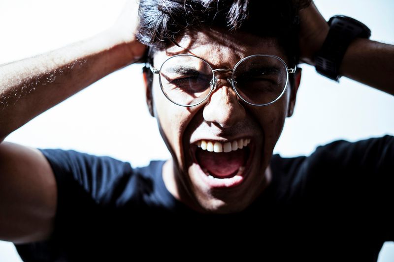 man with glasses yelling in frustration