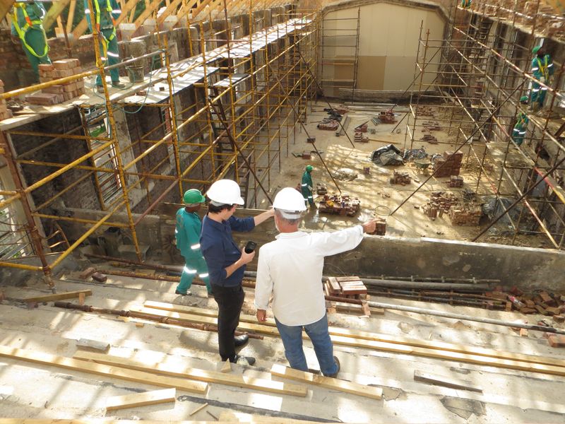 A construction yard. Several workers and managers wearing hard hats perform various functions on site.