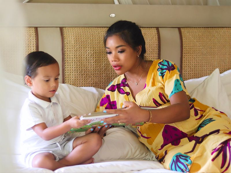 Woman sitting on bed with toddler reading LGBTQ+ picture books together