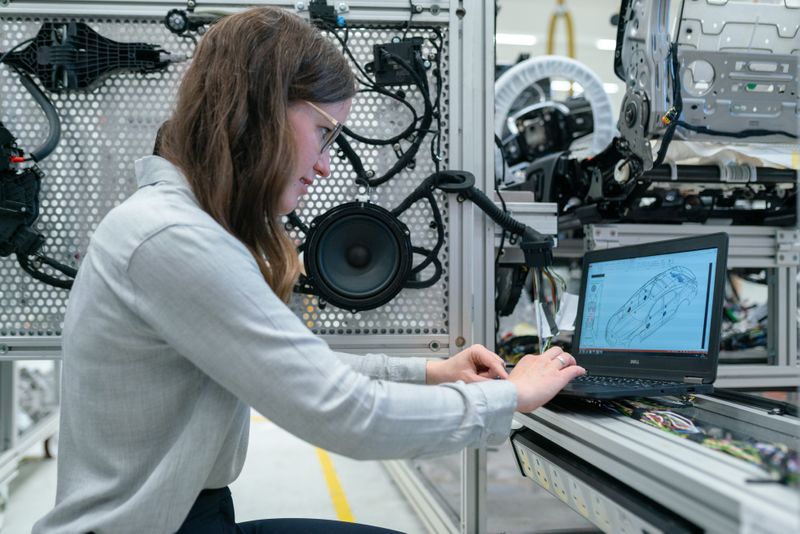 A woman working on a laptop in an electronics workshop