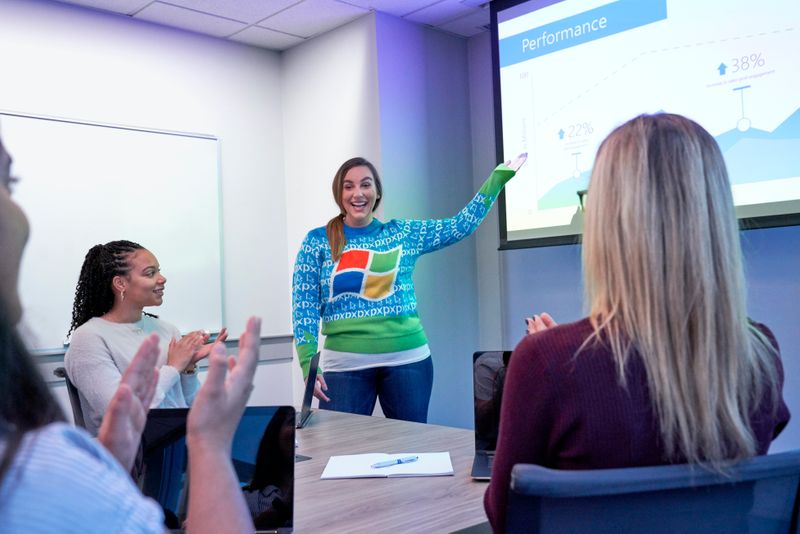 Woman giving a presentation to clapping colleagues in front of a screen.