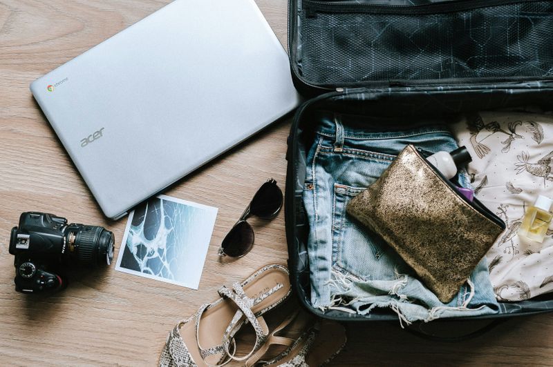 Various items being packed in a suitcase ready for travel.