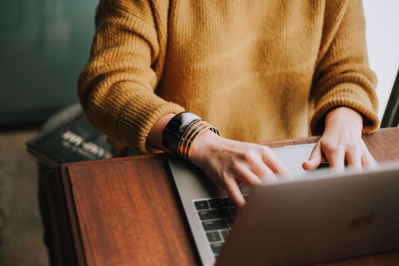 A person typing on a laptop, sitting at a table.