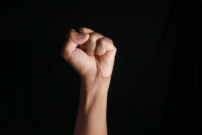 A fist in the air in front of a black background.