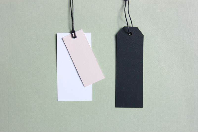 Blank price tags hanging from string on a wall.