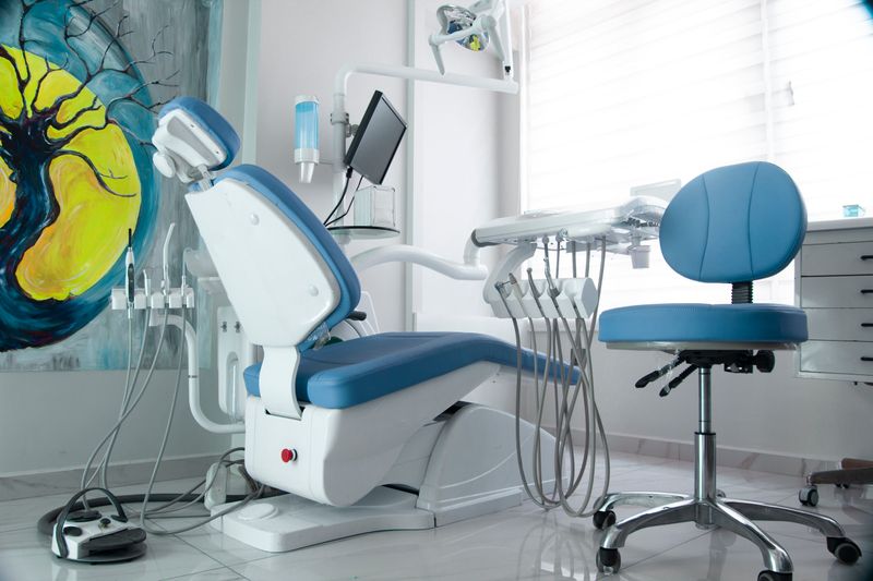 Clean white and blue dentist office with serene painting on the wall and everything laid out for the next patient. 