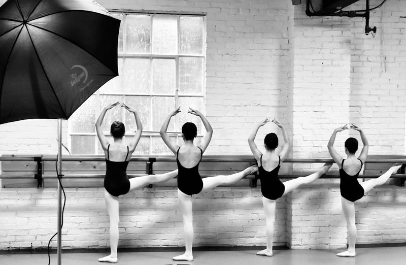 Ballet dancers practicing in a studio against a wall bar.