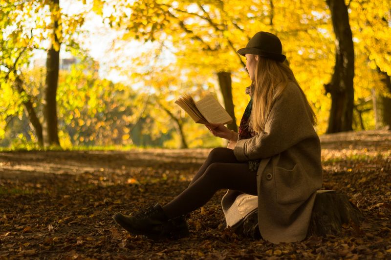 A woman reading a book outdoors.