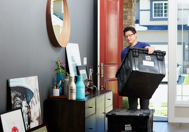 A person holding a big box as they move in to their apartment.