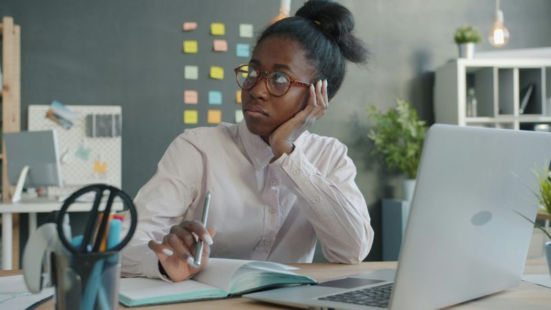 A woman thinking at her work desk.