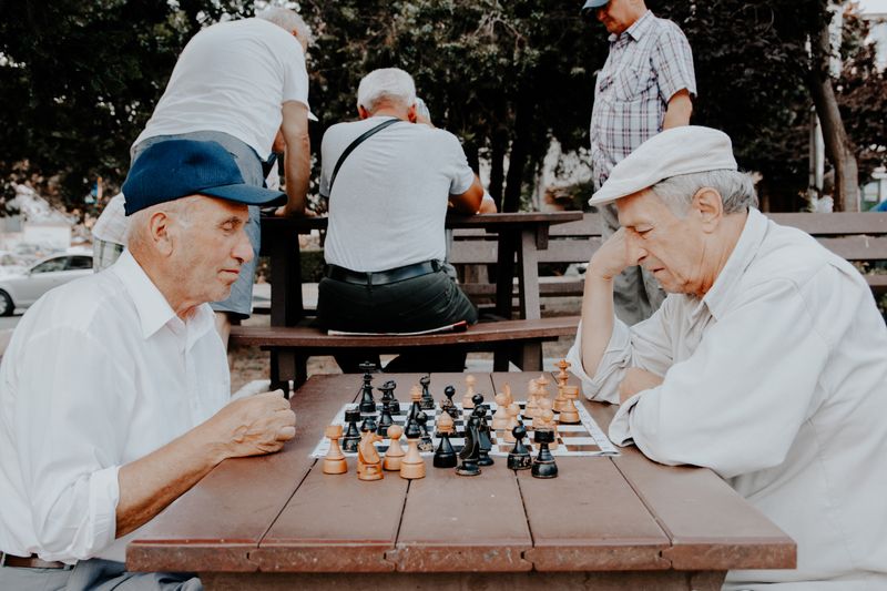 Two elderly male-looking persons playing chess.