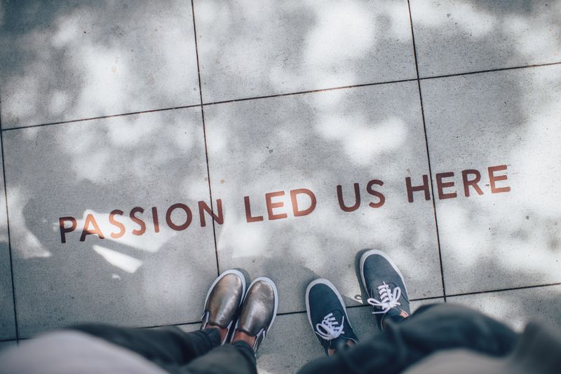 Two people looking down on a sidewalk inscription that reads, 'passion led us here'.