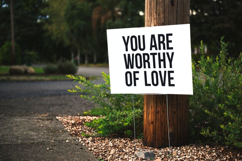 A sign by a tree that says 'You are worthy of love.'