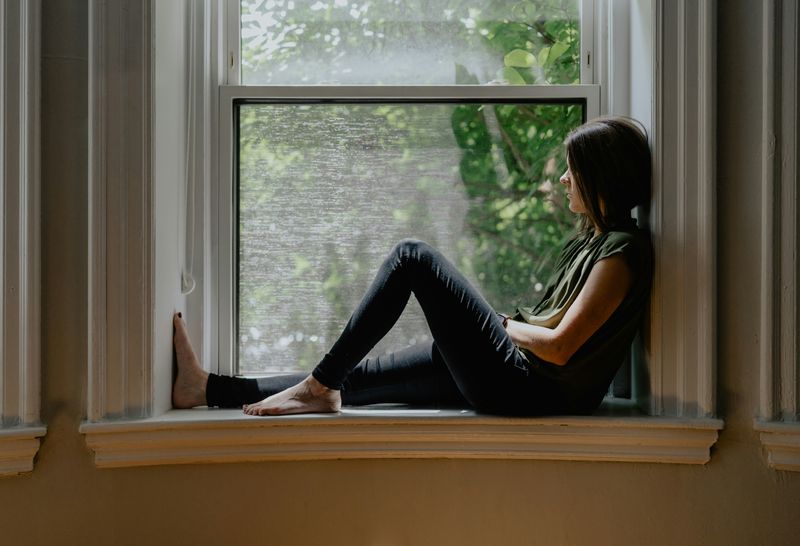 Image of a person sitting by the window thinking