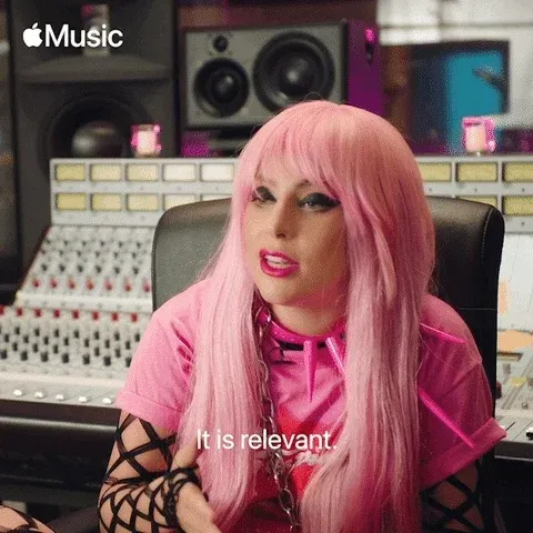 GIF: Lady Gaga sits in recording studio with pink hair and pink tshirt and declares, 'It is relevant.'