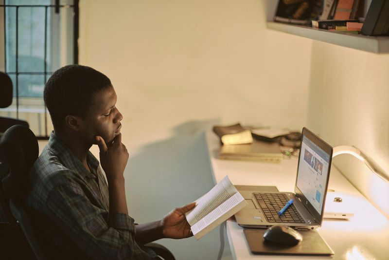 A man reading from a book at his desk.