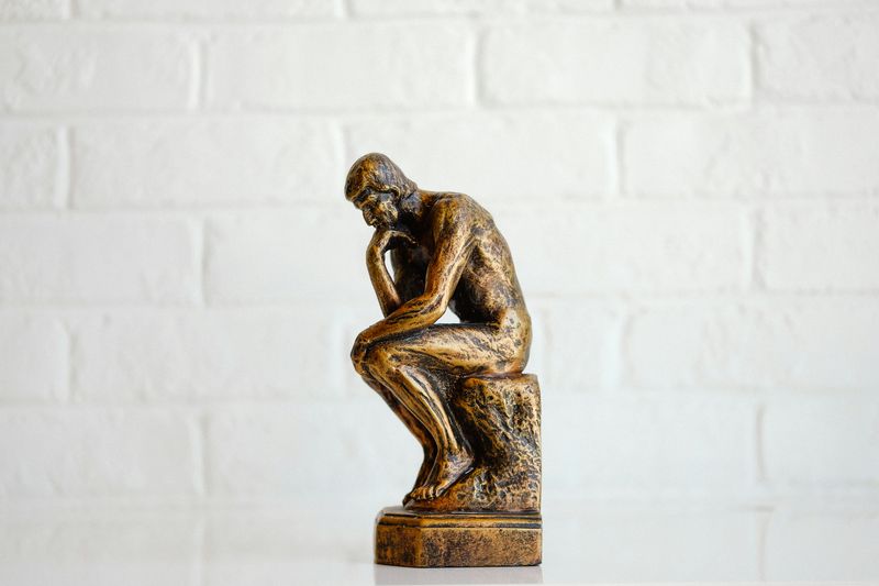 A miniature bronze statue of a person thinking.